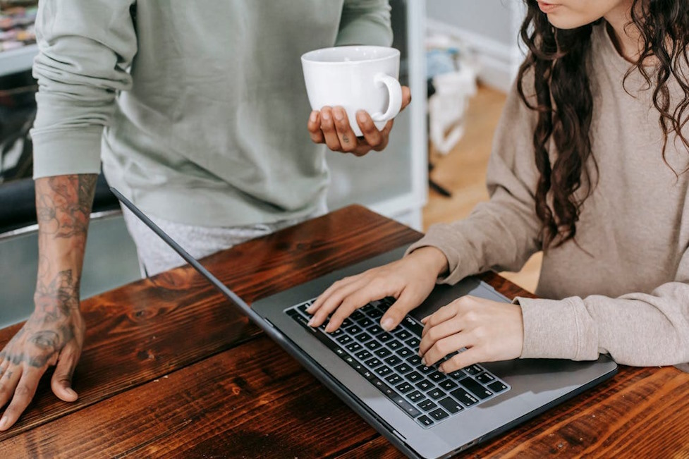 Homme et femme échangeant au-dessus d’un ordinateur portable, illustrant le travail à distance.
